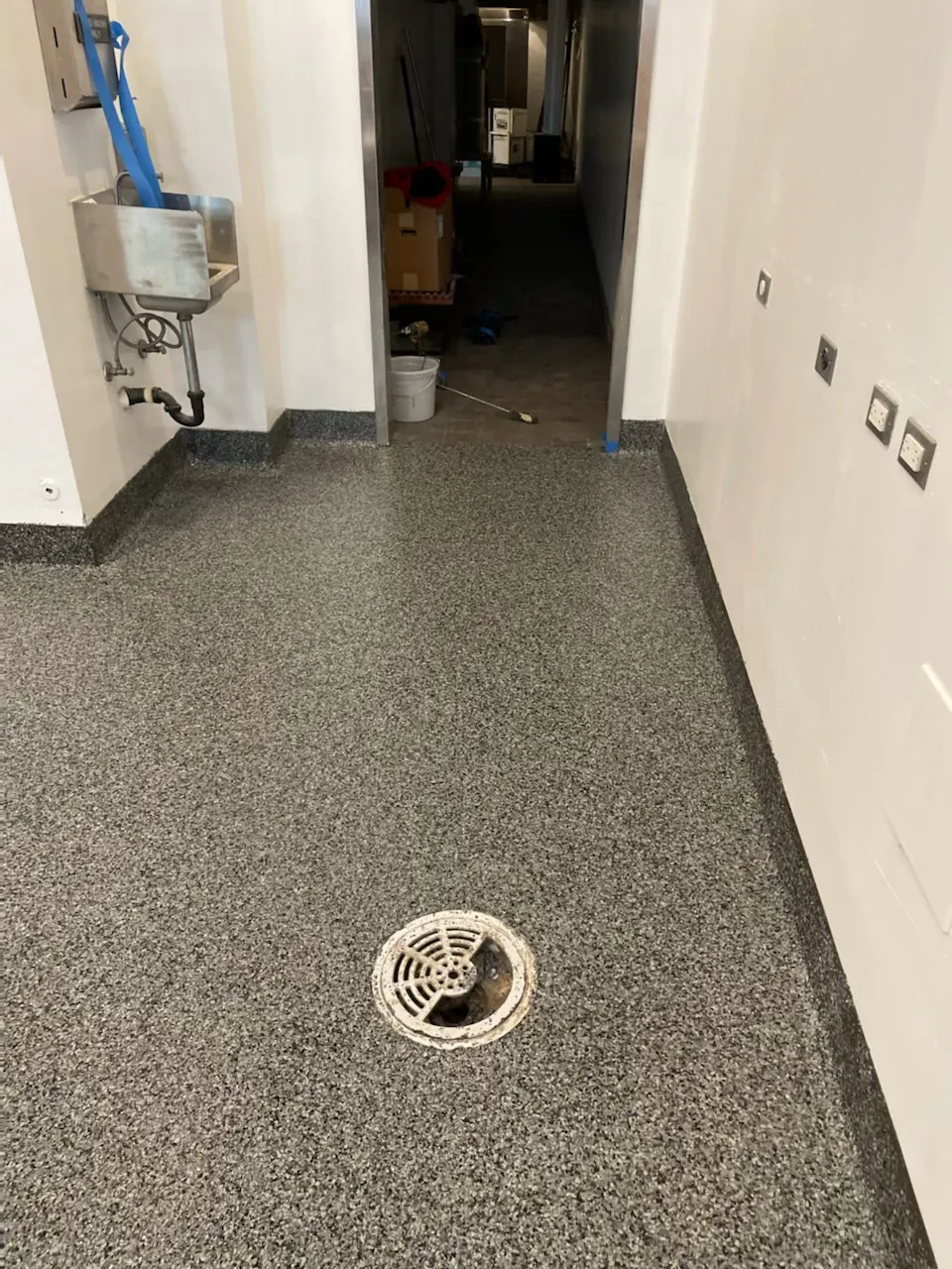 Flake epoxy floor with a floor drain in a commercial service hallway