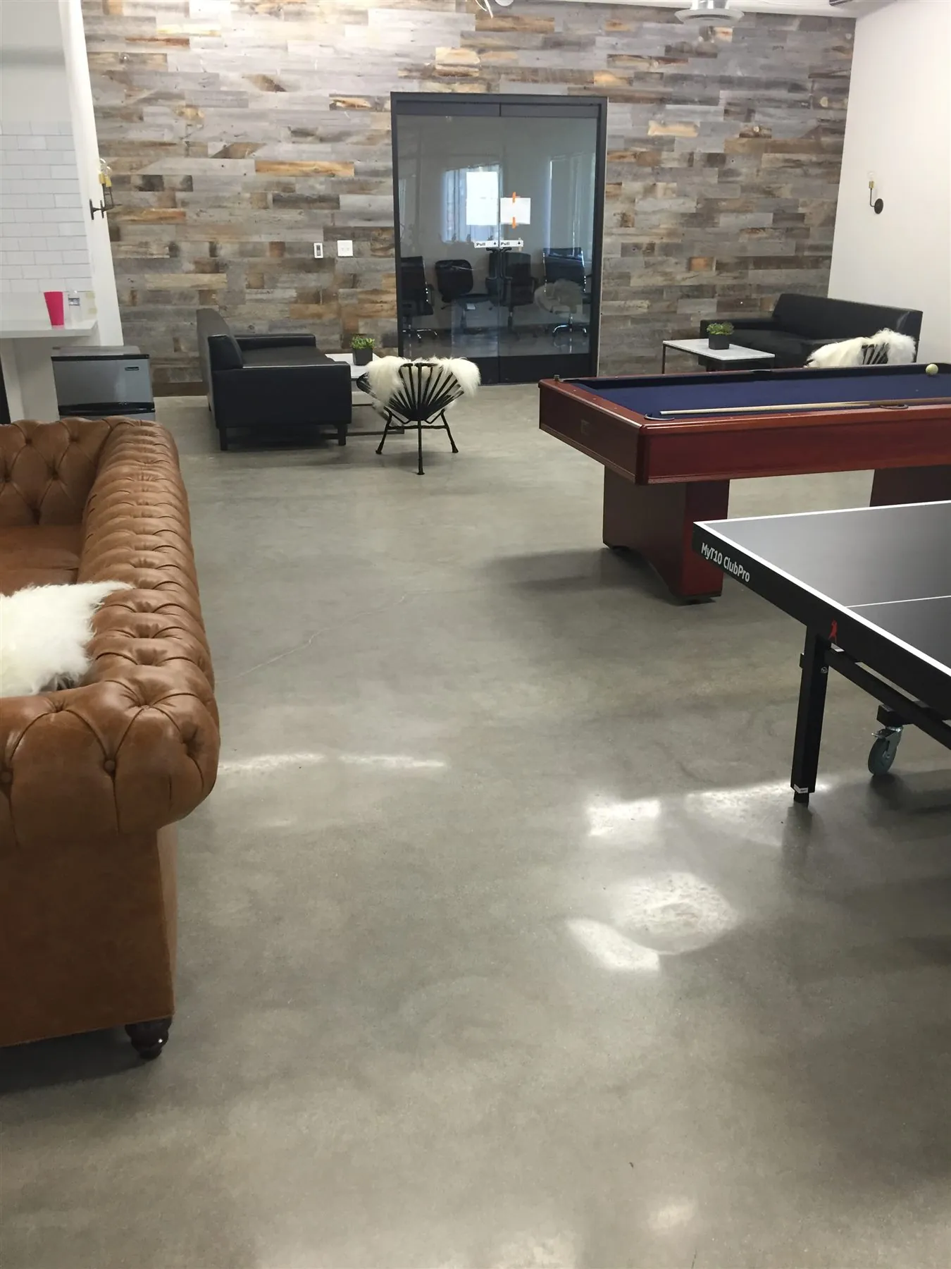 Polished concrete floor in a game room with a stone accent wall