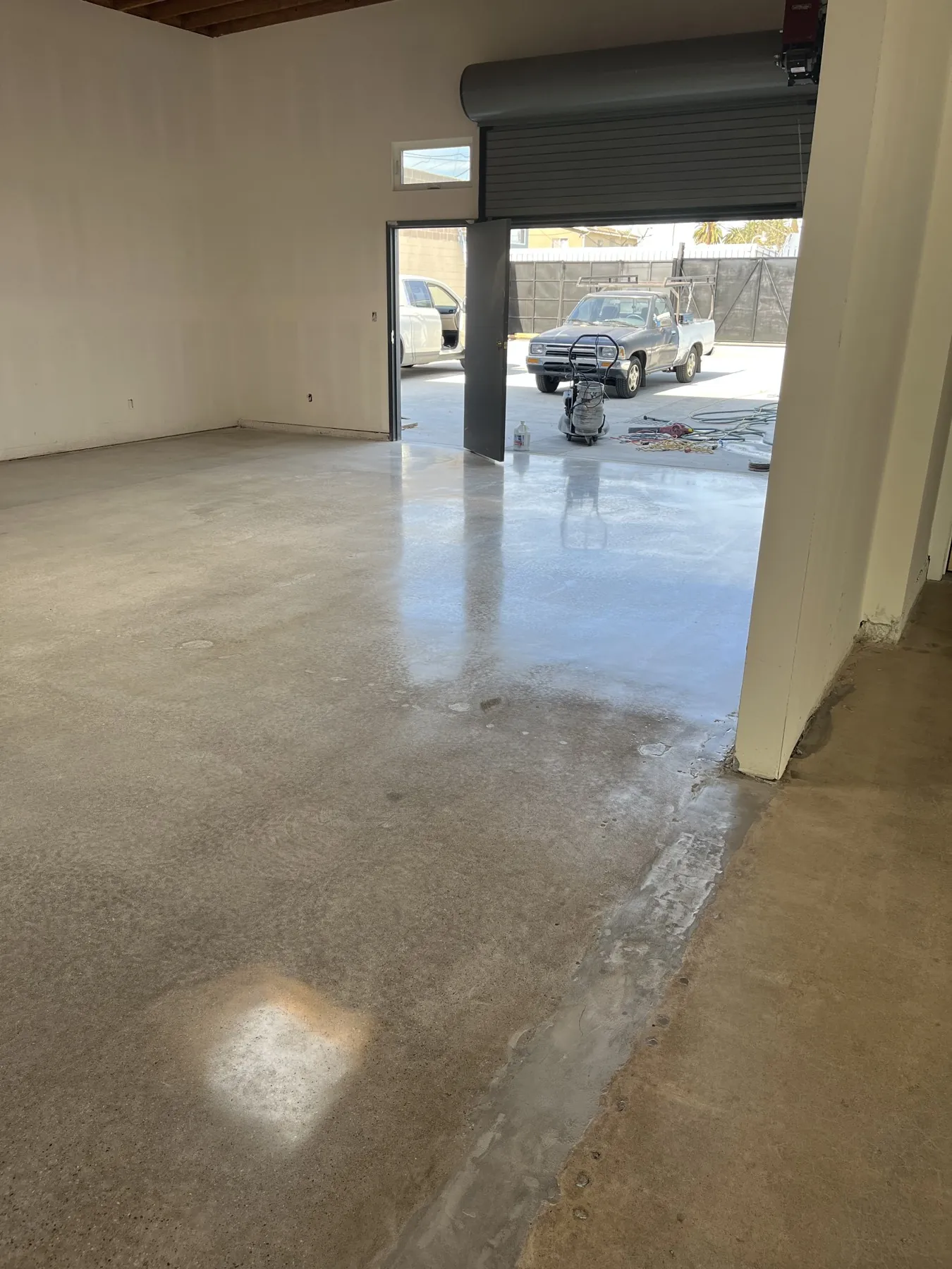 Polished concrete floor in a garage workshop with a roll-up door