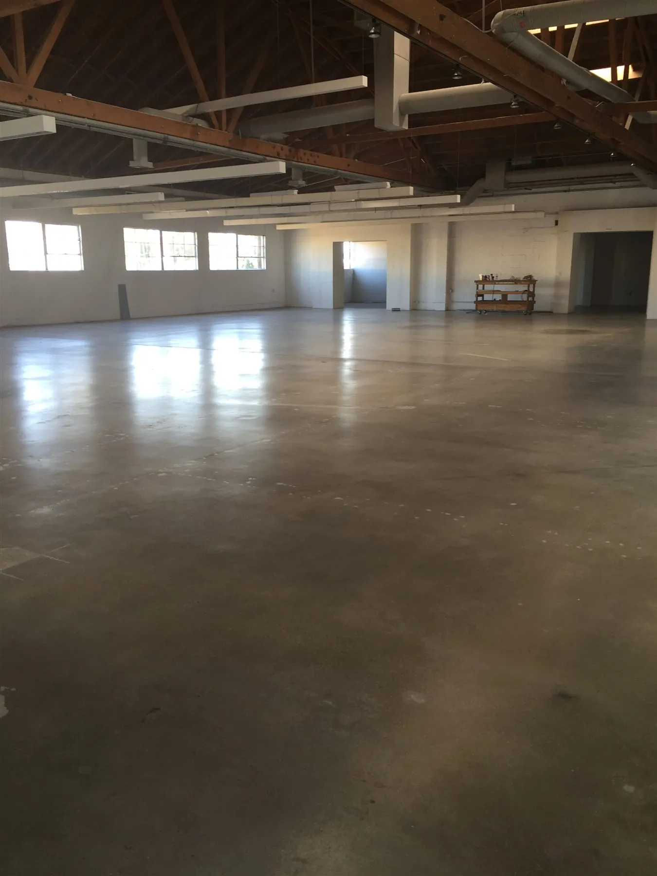 Polished concrete warehouse floor under a wood truss roof