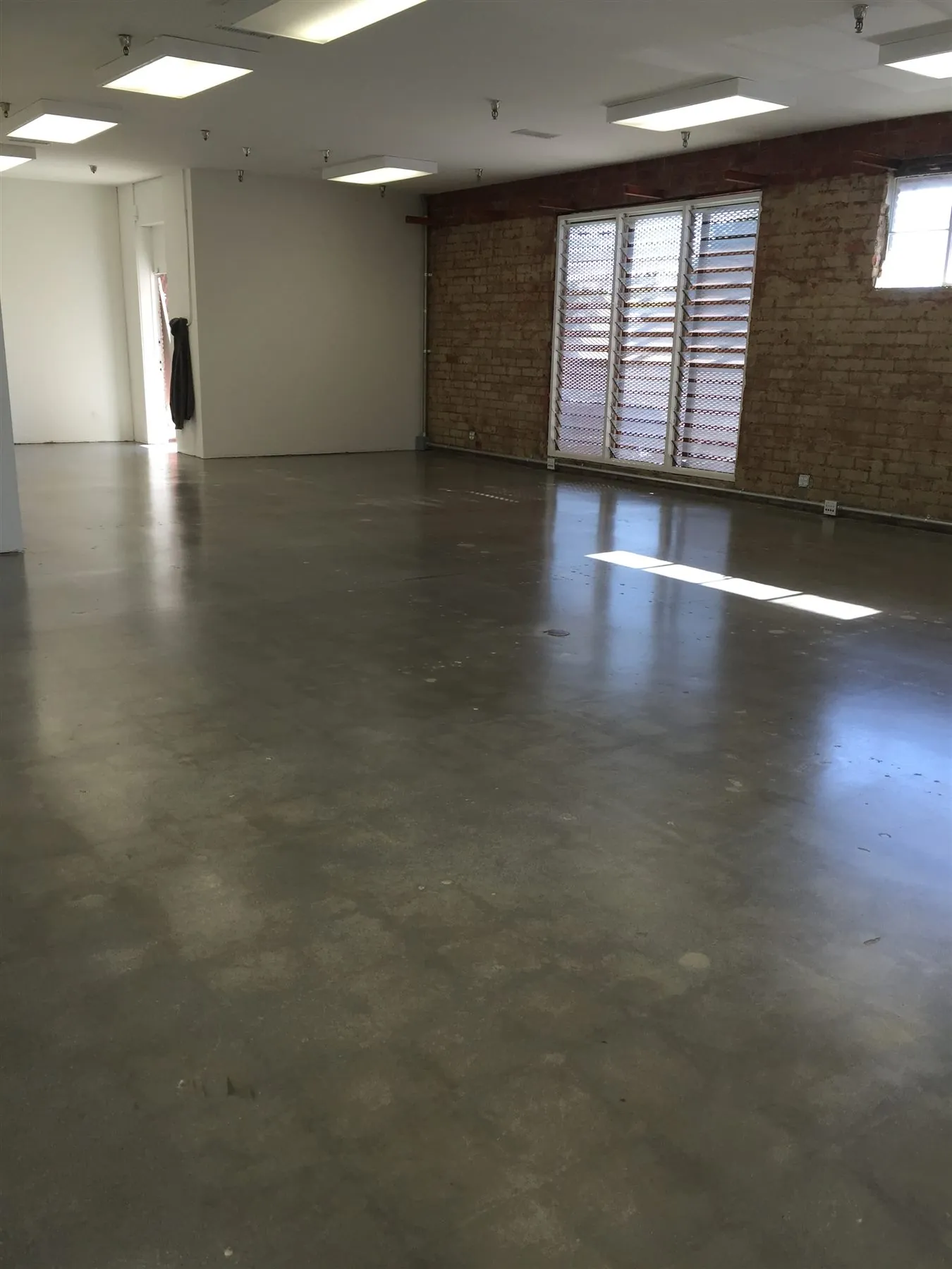 Satin polished concrete office floor with a brick wall