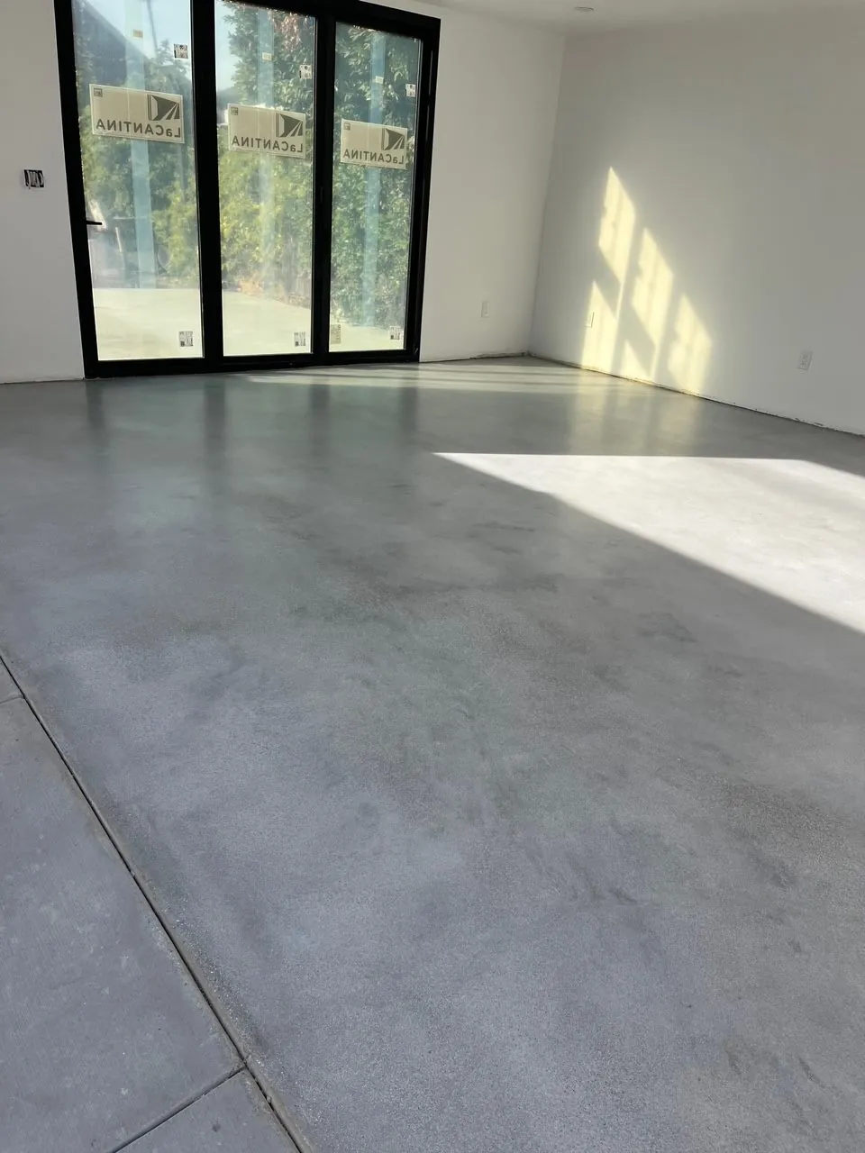 Sealed grey concrete floor in a bright room with sliding glass doors