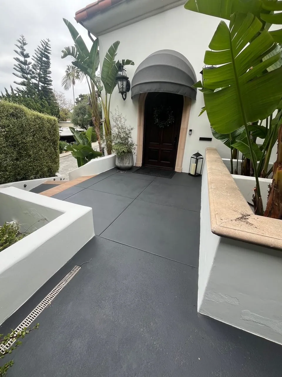 Dark grey stained concrete entry walkway at a Spanish-style home